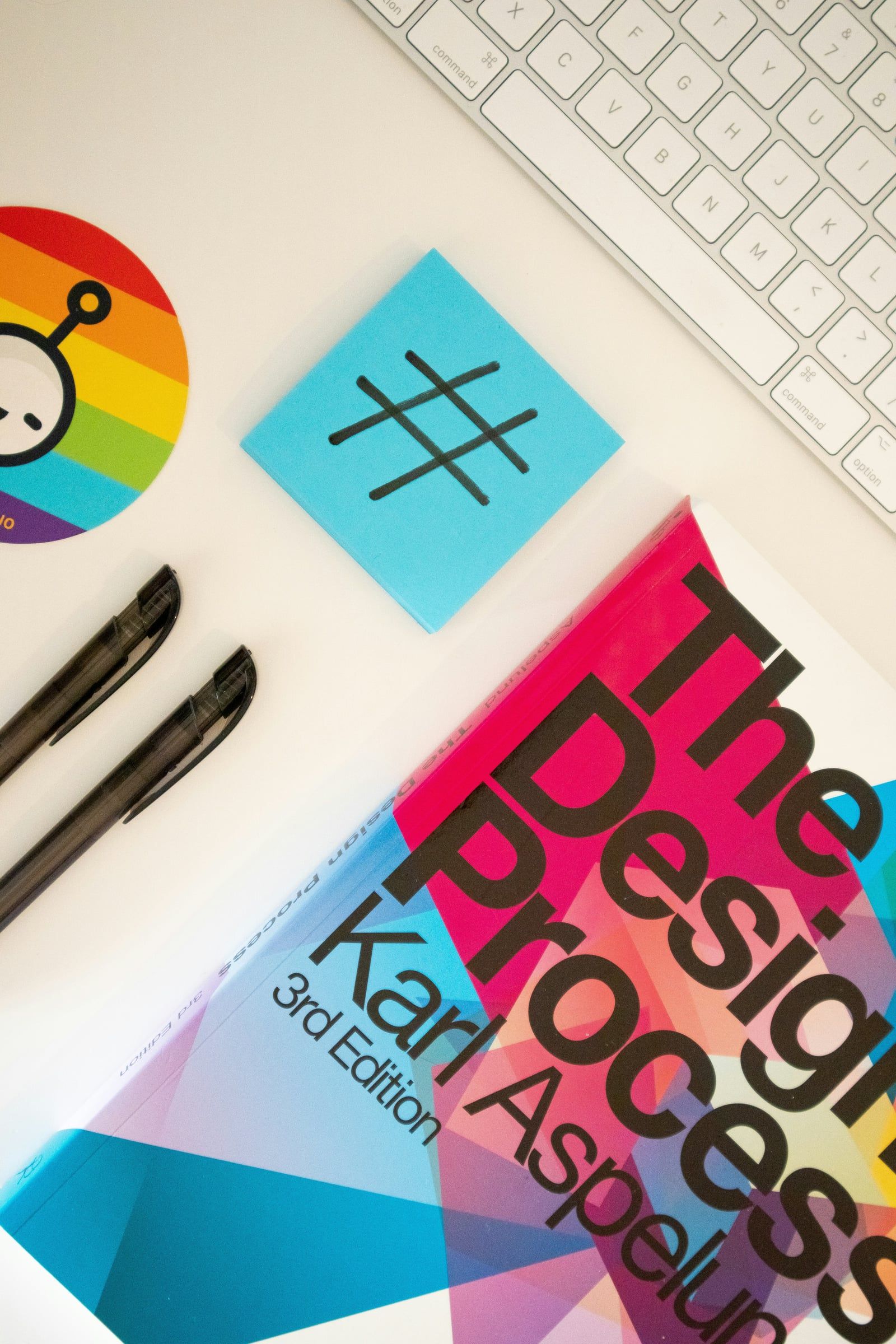 Design book, pens and sticky notes beside a keyboard