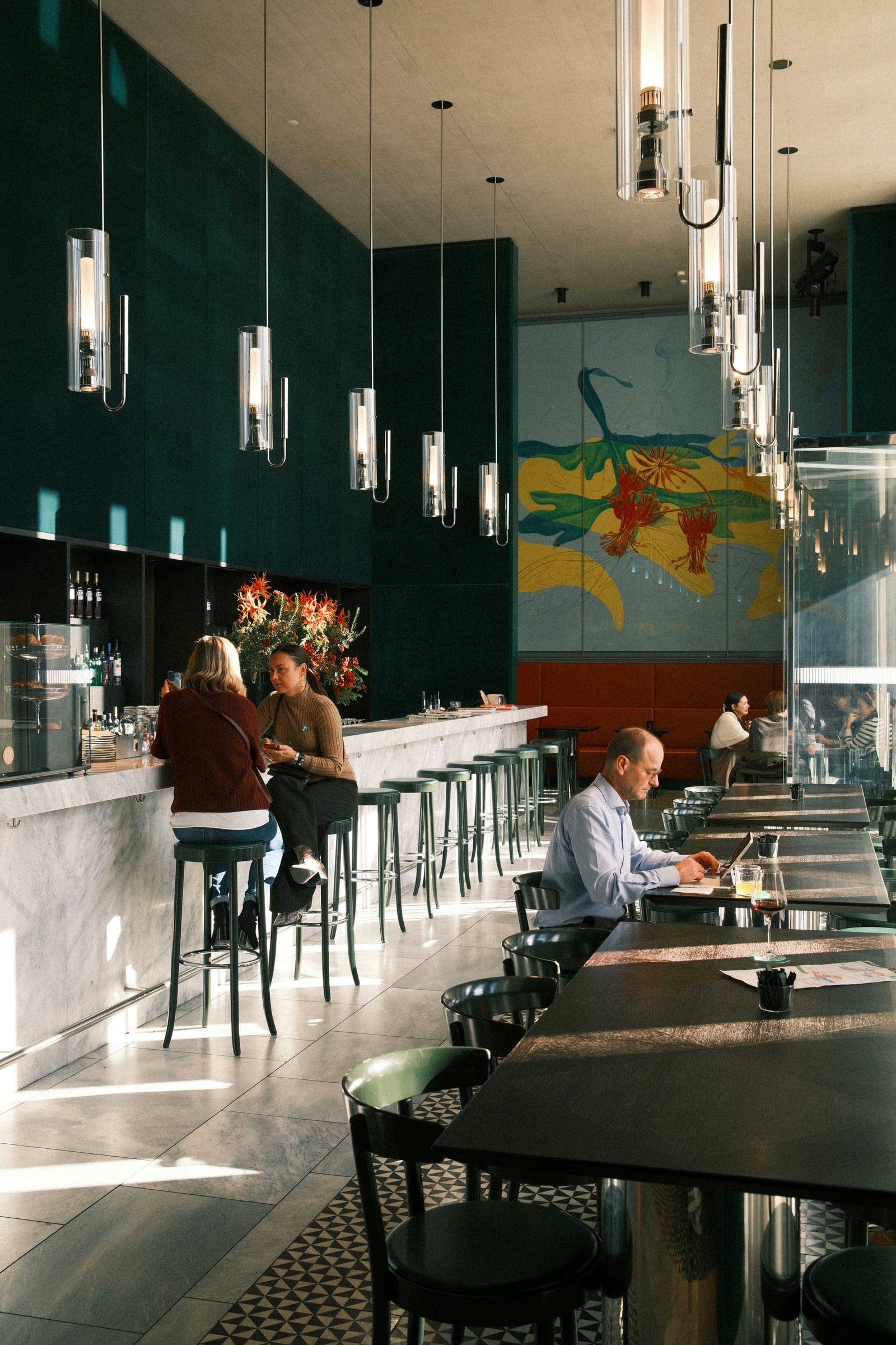 Long café bar with pendant lights and people sitting at tables