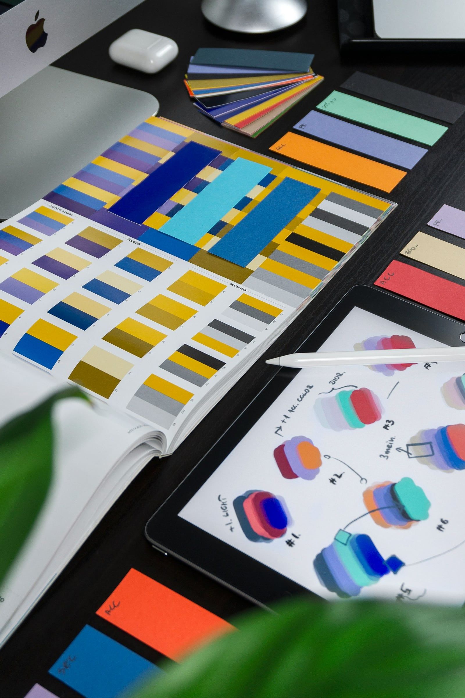 Colour swatches and logo sketches on a tablet beside a keyboard